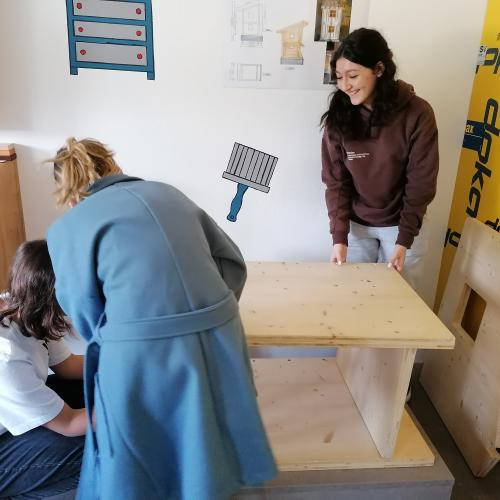 Schülerinnen beim Verarbeiten einer Holzplatte