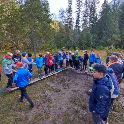 Kinder stehen auf dünnen Holzbrettern und spielen Geschicklichkeitsspiele